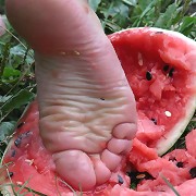 Pretty little feet playing with a watermelon